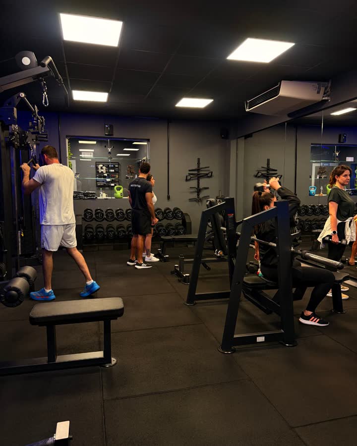 Instrutor acompanhando alunos durante um treino de musculação na Revoo